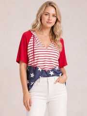 Model standing in a red, white, and navy stars-and-stripes drawstring hoodie shirt with short sleeves, a V-neck, and a relaxed silhouette.