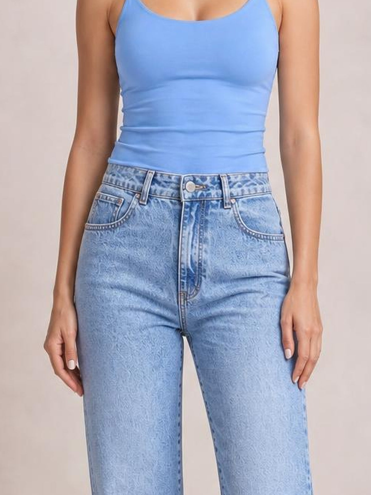 Model wearing light blue straight jeans with front pockets, belt loops, button closure, and a classic five-pocket construction, standing with hands at her sides.