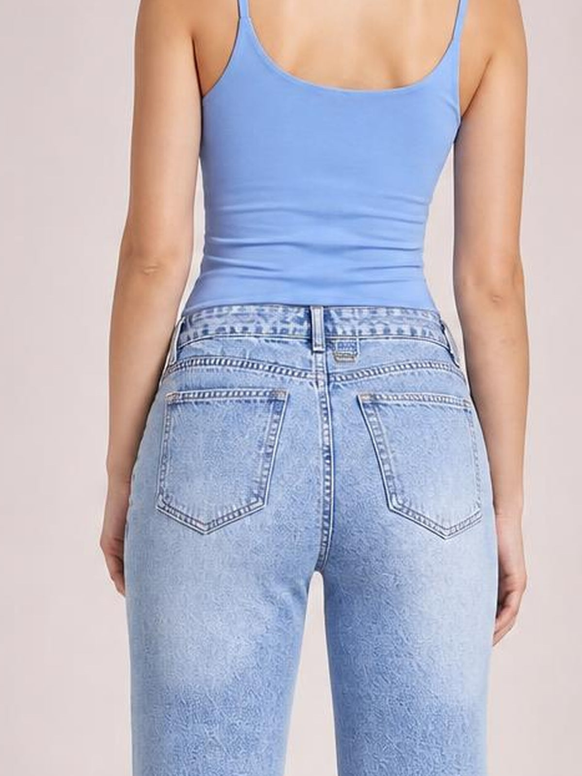 A model stands in a rear view wearing light blue straight jeans with a structured waistband, belt loops, contrast stitching, and two back pockets.