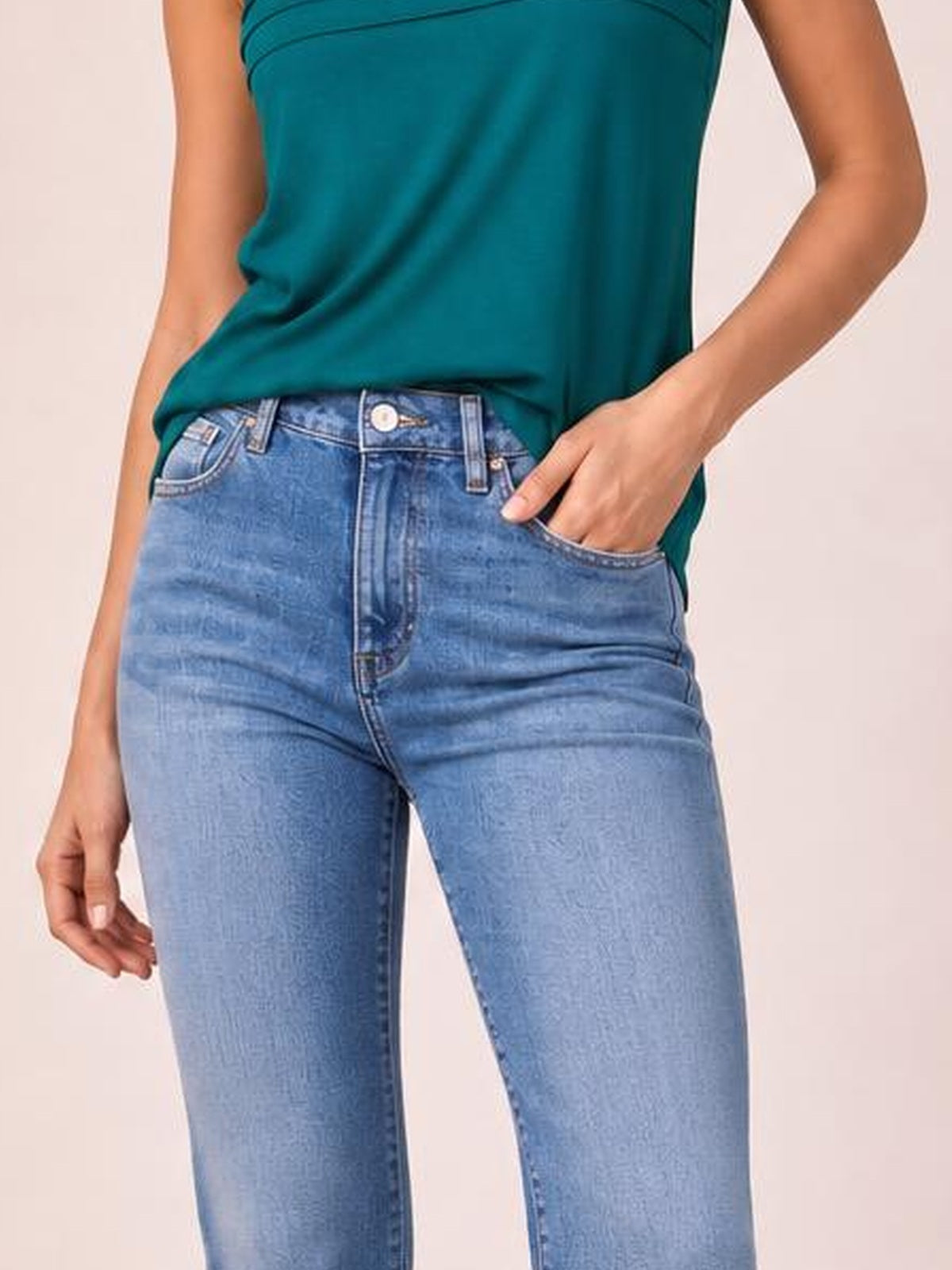 Model wearing light blue straight-leg jeans with front pockets, belt loops, button closure, and classic five-pocket construction, with one hand tucked into a pocket.