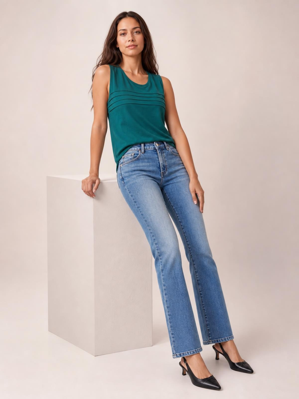 Model leans against a block wearing light blue straight-leg jeans with front pockets, belt loops, button closure, and a full-length silhouette.