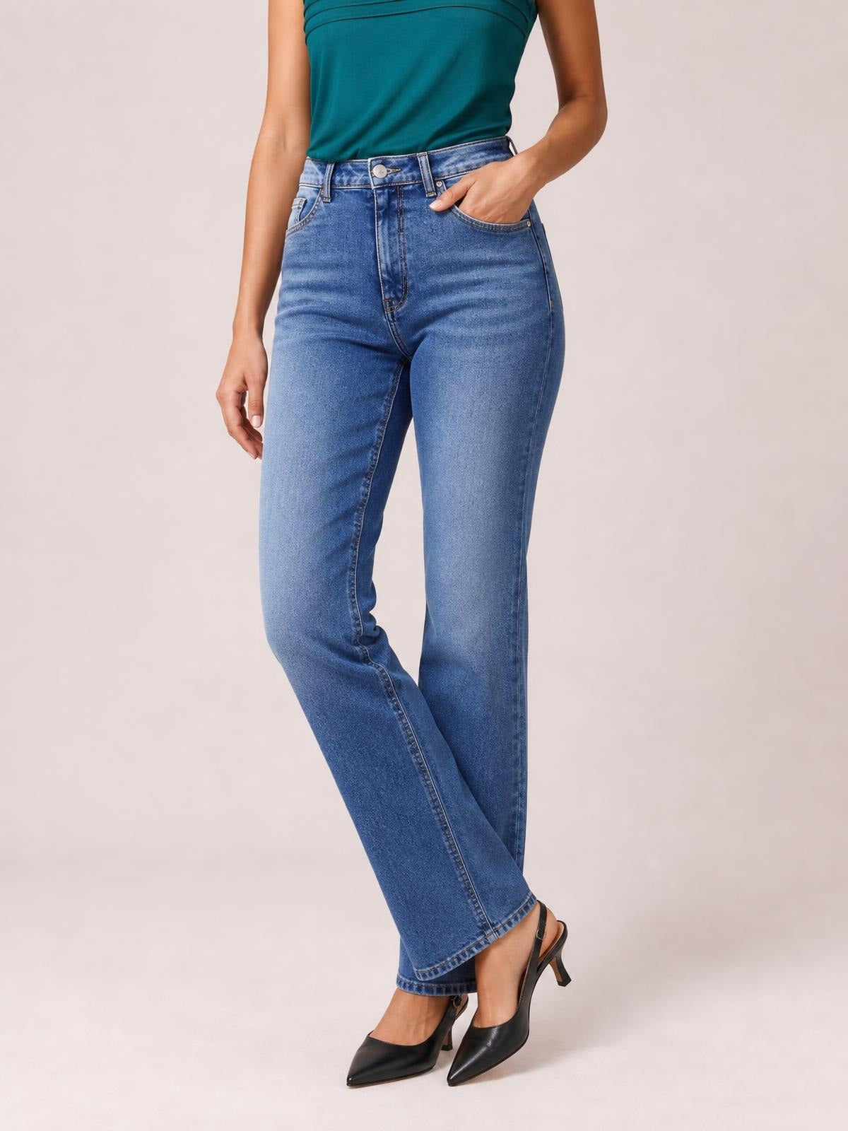 Model poses with one hand in the pocket of blue straight leg jeans, showing a high waist, classic five-pocket construction, and relaxed full-length silhouette.