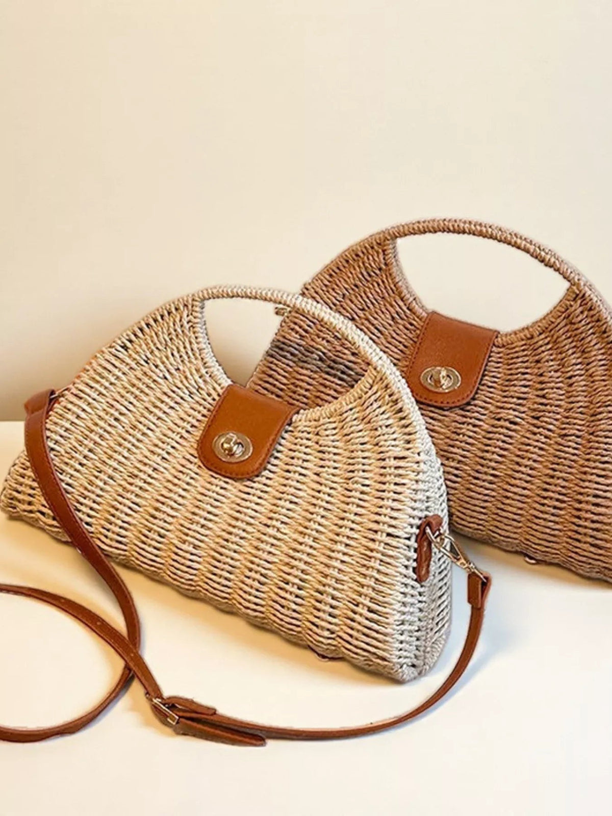 Medium straw-woven crossbody bag with a rounded silhouette, adjustable brown strap, leather flap closure, and visible woven construction.
