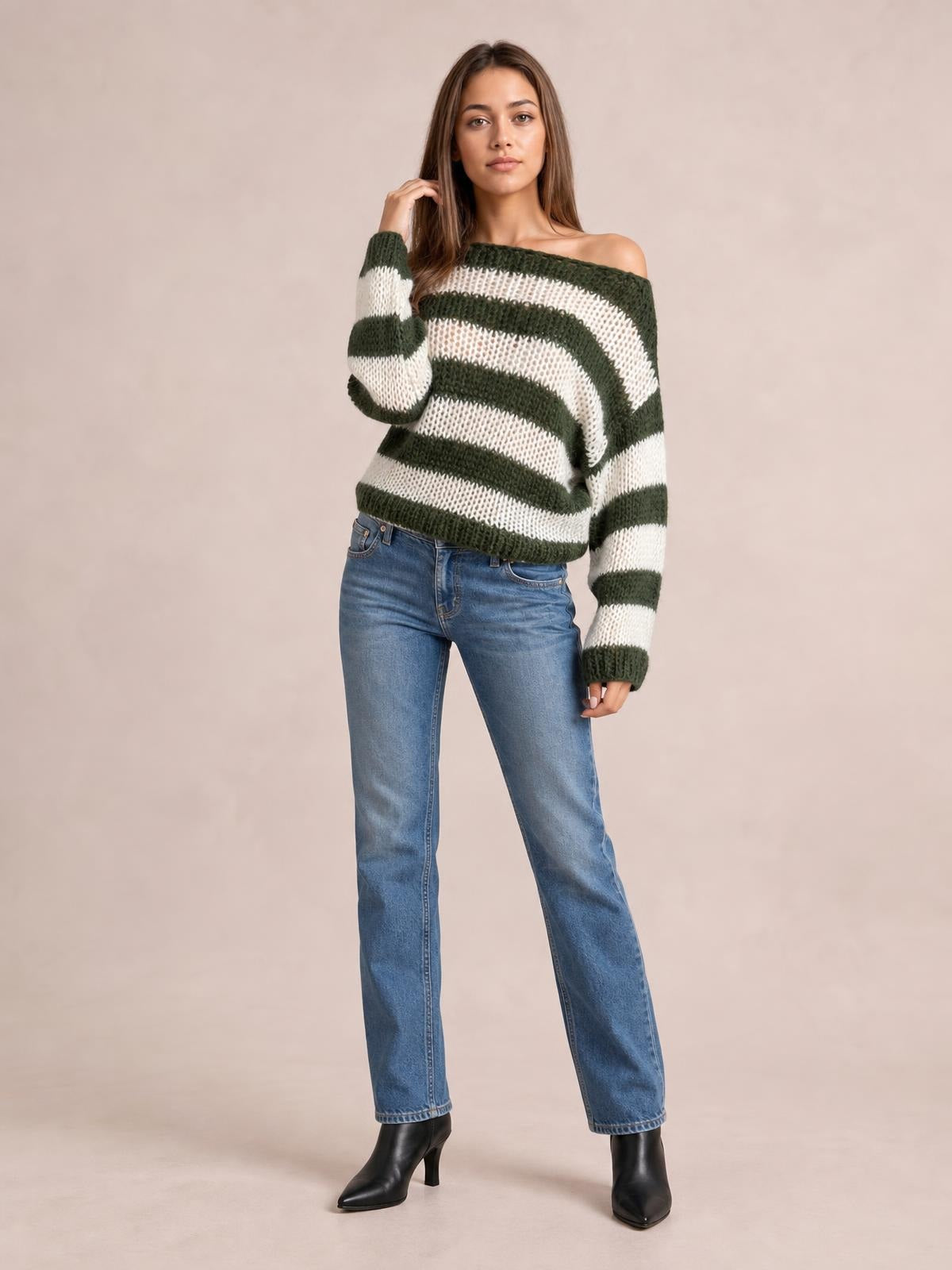 Model poses in a relaxed stance wearing a green and white striped boat neck long sleeve sweater with a loose, chunky-knit silhouette.