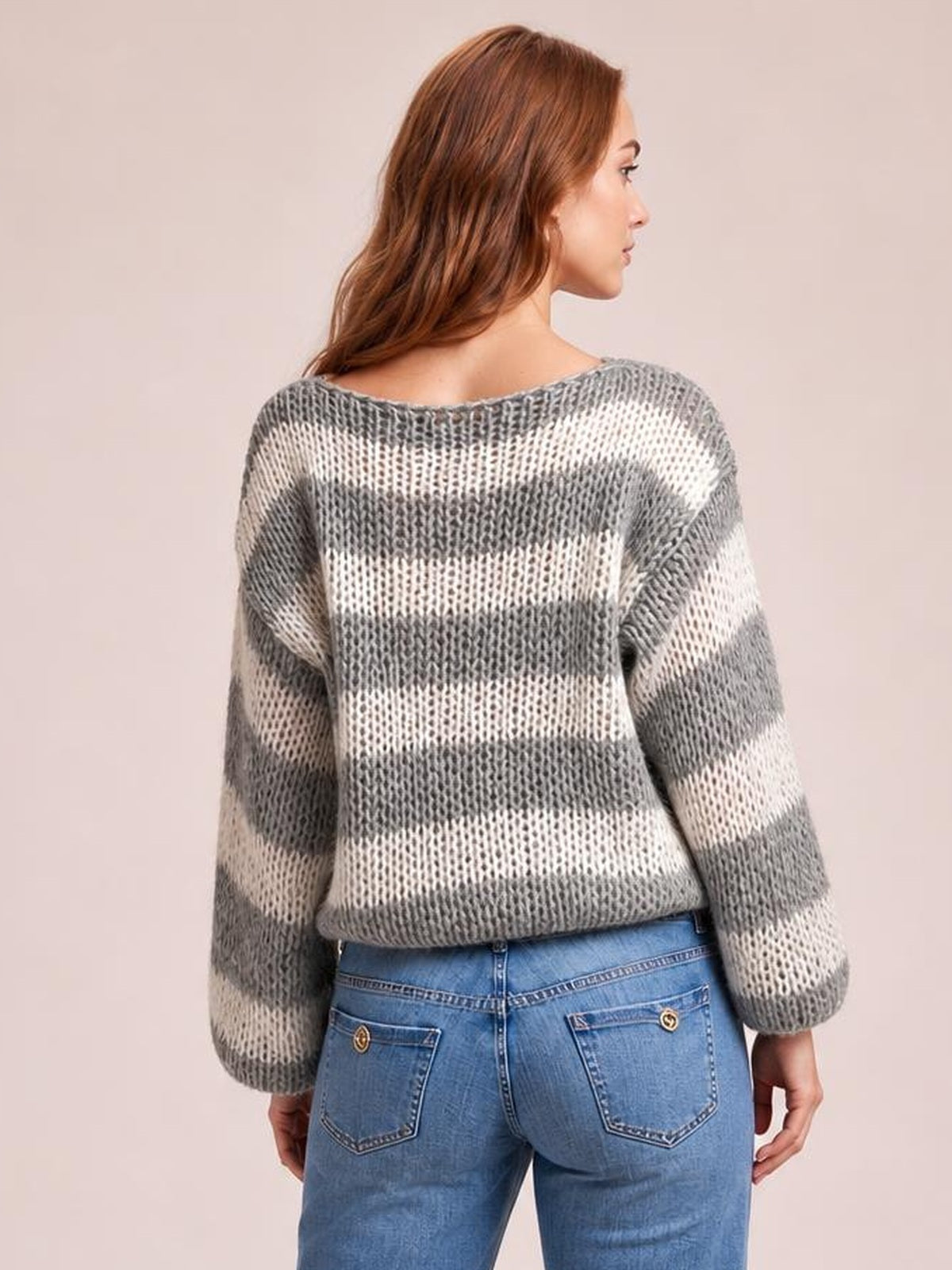 A model shown from behind wears a gray and white striped boat neck sweater with long sleeves, an open knit texture, and a relaxed silhouette.