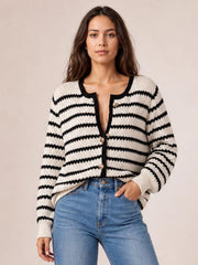 Model wears a cream and black striped button-up long-sleeve cardigan with a relaxed silhouette, ribbed cuffs, and front buttons, posing with one hand in her jeans pocket.