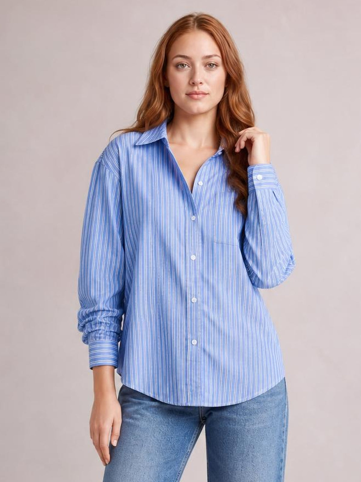 Model wearing a blue and white striped button-up long-sleeve shirt with a collared neckline, buttoned front, buttoned chest pocket, and relaxed curved hem.