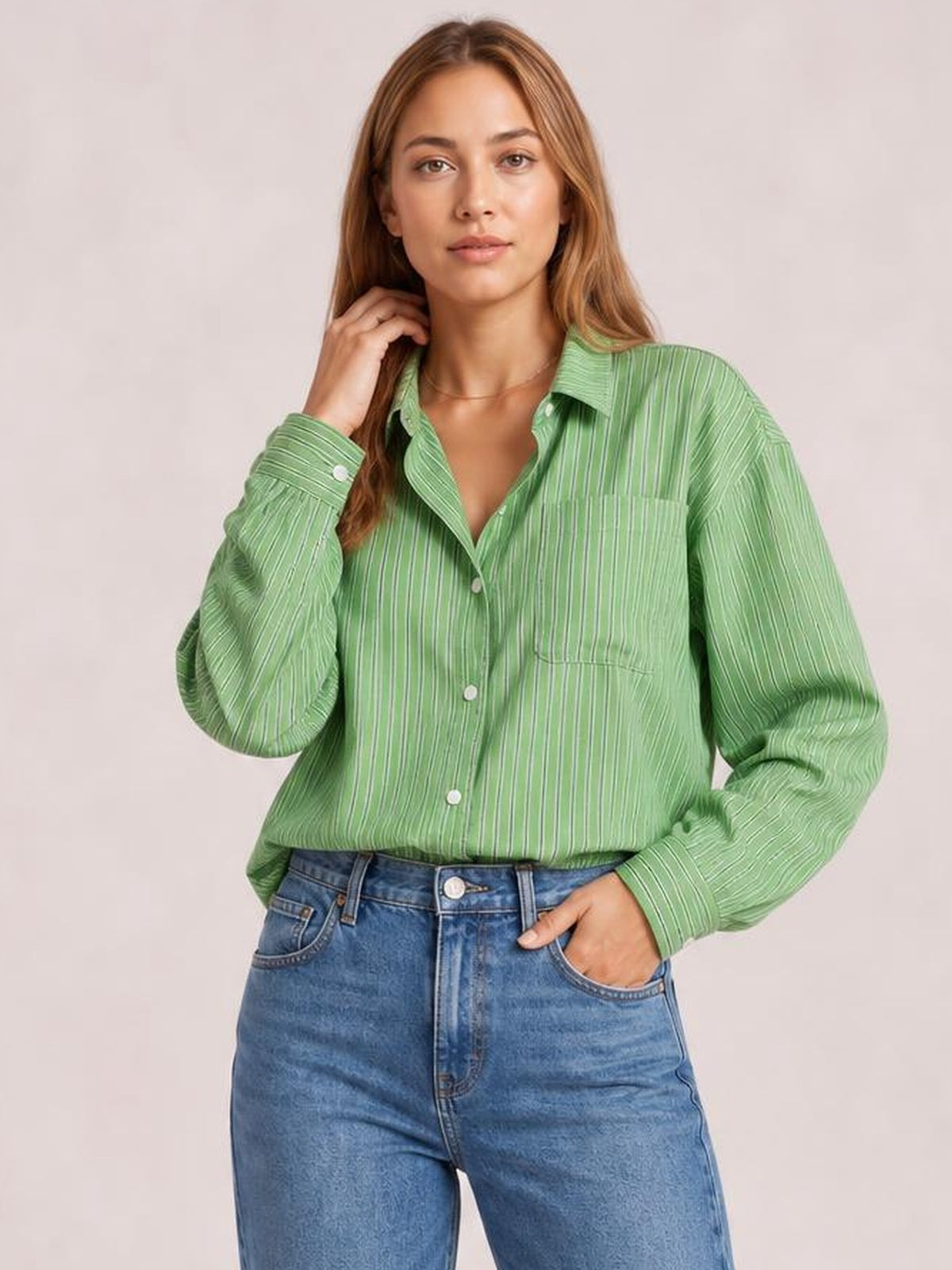 Model wearing a green striped button-up long sleeve shirt with a relaxed silhouette, pointed collar, buttoned chest pockets, and rolled cuffs.
