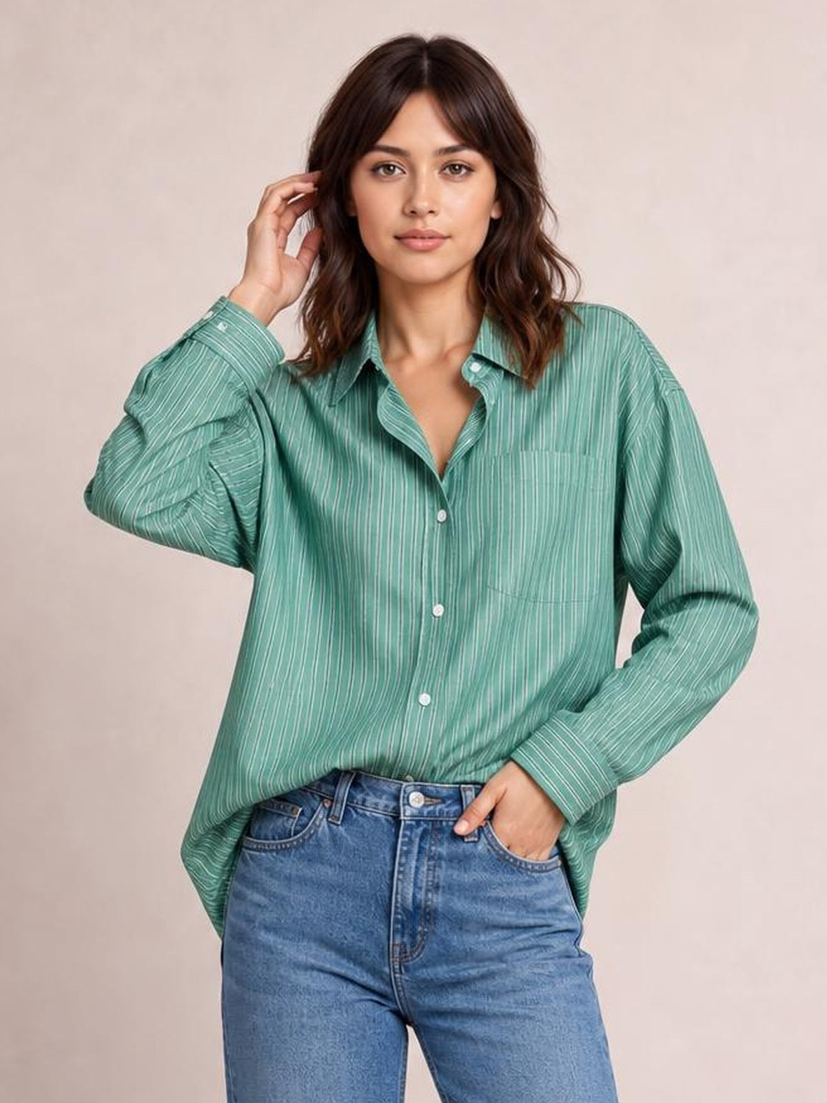 Model wearing a teal striped button-up long sleeve shirt with a relaxed silhouette, collared neckline, buttoned chest pockets, and curved hem.
