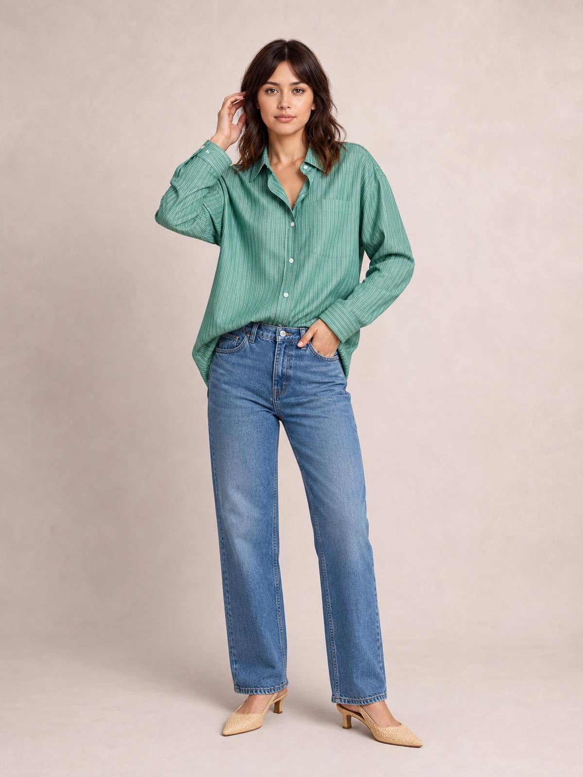 Model poses in a loose green striped button-up long sleeve shirt with a collar, button front, and chest pocket.