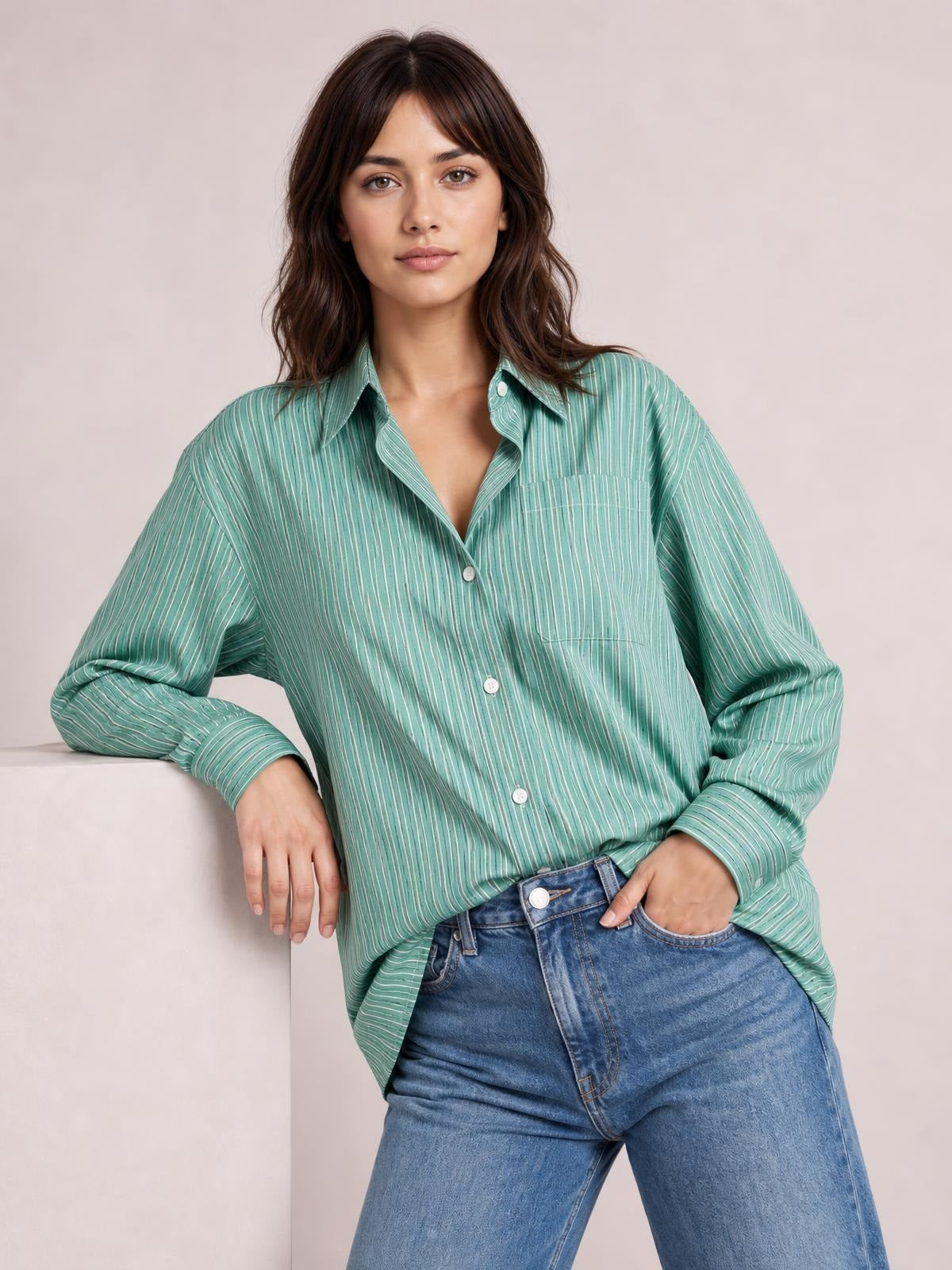 Model wears a teal striped button-up long sleeve shirt with a collared neckline, buttoned chest pocket, relaxed silhouette, and rolled cuffs.