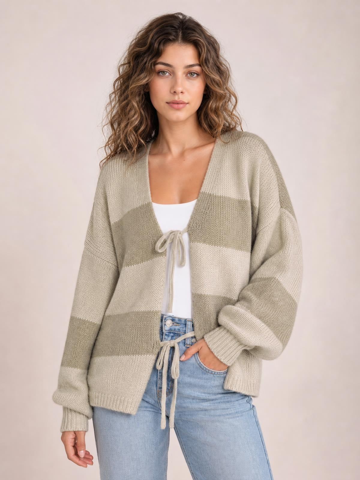 Model wears a taupe and cream striped color block sweater cardigan with a relaxed silhouette, balloon sleeves, ribbed cuffs, and tie-front closure.