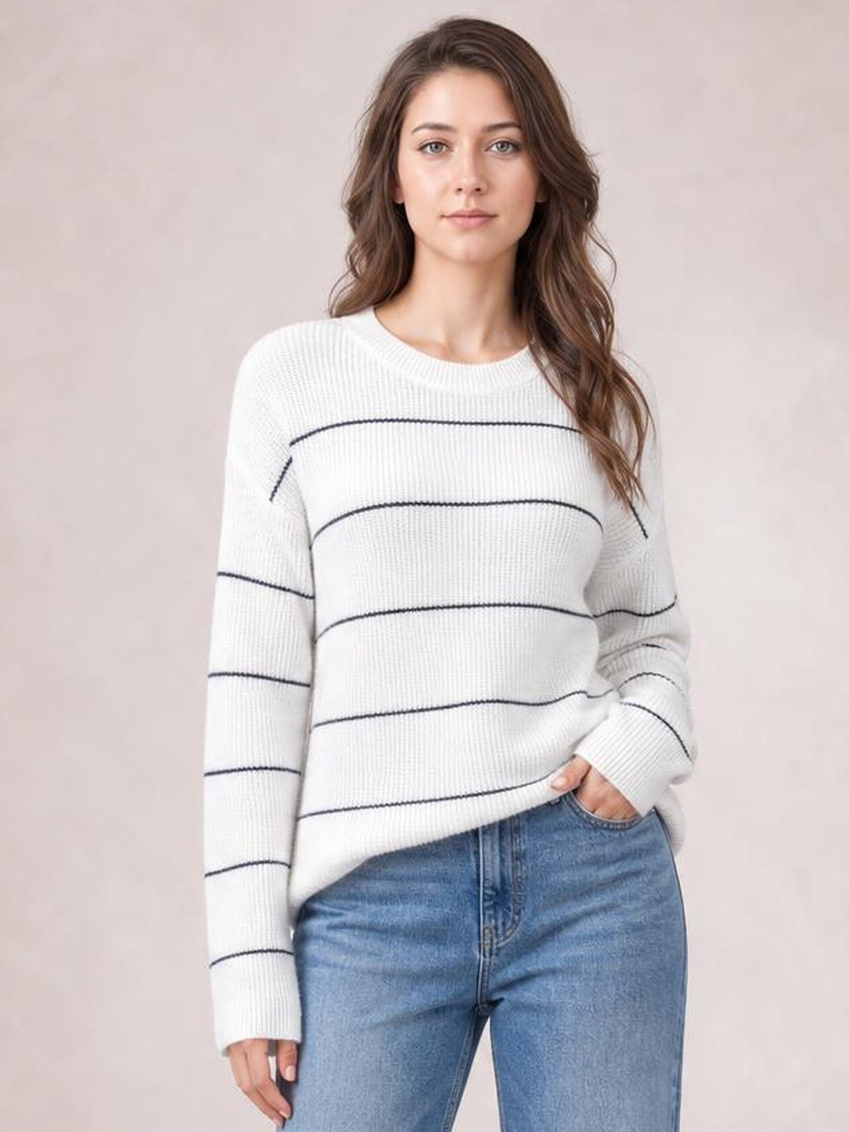 Model wearing a white striped crew neck sweater with dropped shoulders, ribbed knit construction, long sleeves, and a relaxed silhouette.