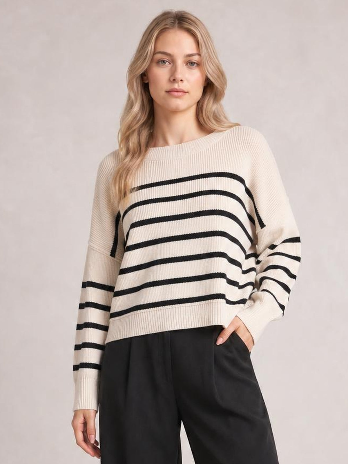 Model wearing a cream and black striped pullover sweater with a round neck, dropped shoulders, long lantern sleeves, and a regular relaxed silhouette.