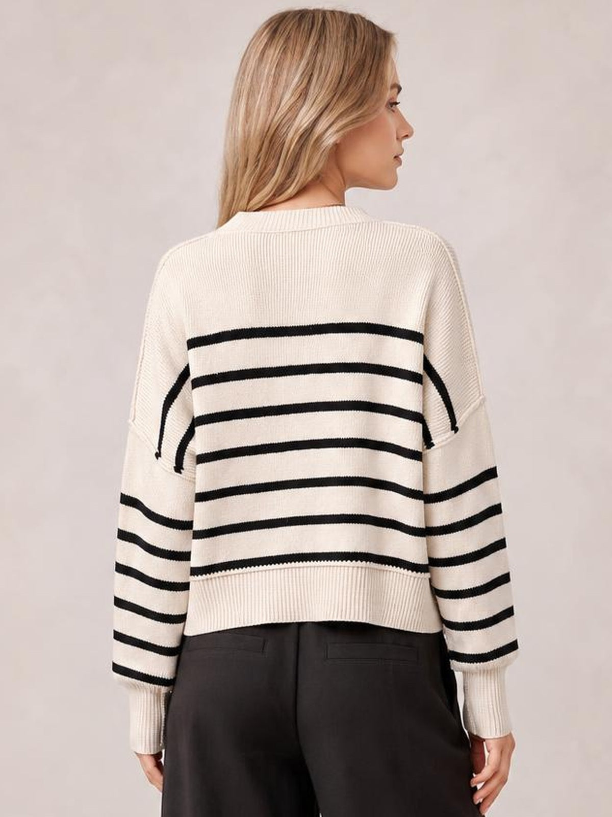 Model shown from behind wearing a cream striped dropped-shoulder round-neck pullover sweater with black horizontal stripes and lantern sleeves.