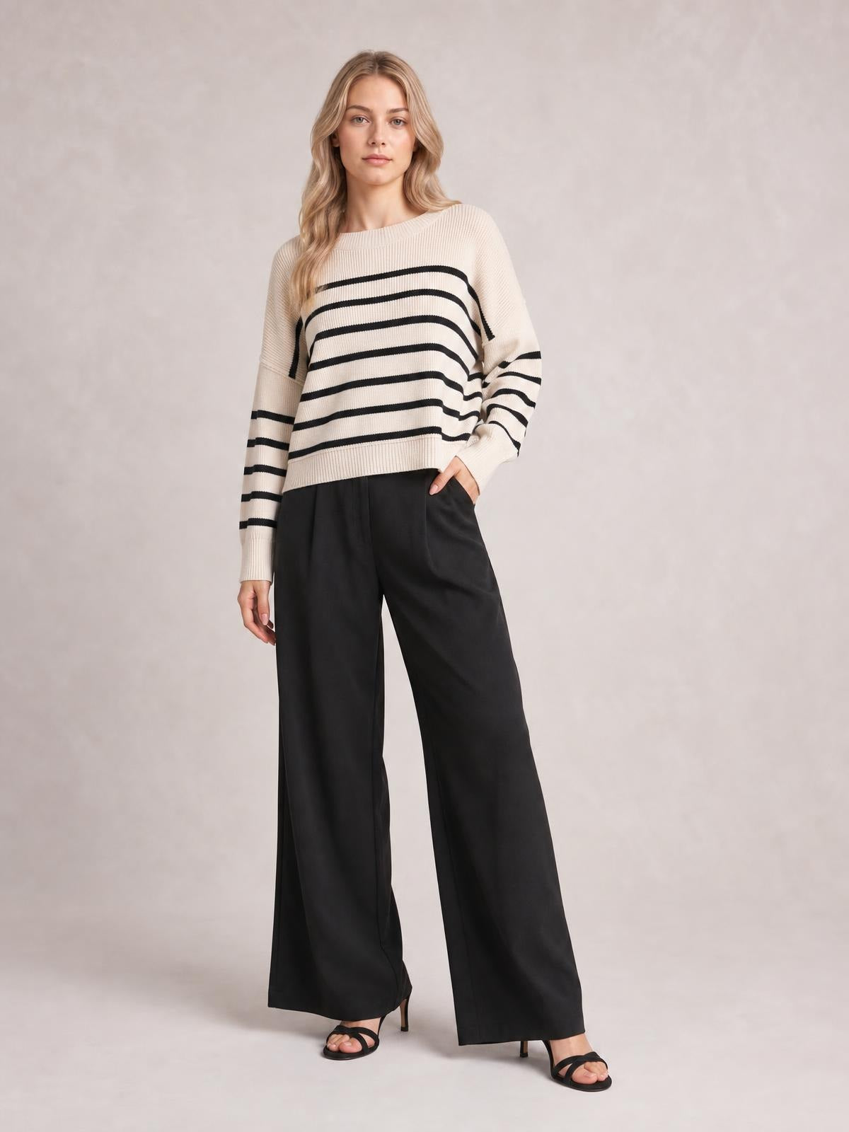 Model wears a cream and black striped round-neck pullover sweater with dropped shoulders, long lantern sleeves, ribbed trim, and a relaxed regular-length silhouette.