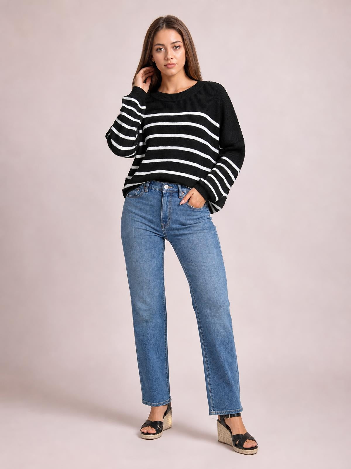 A model poses in a black-and-white striped dropped-shoulder pullover sweater with a round neck, relaxed silhouette, and long lantern sleeves.