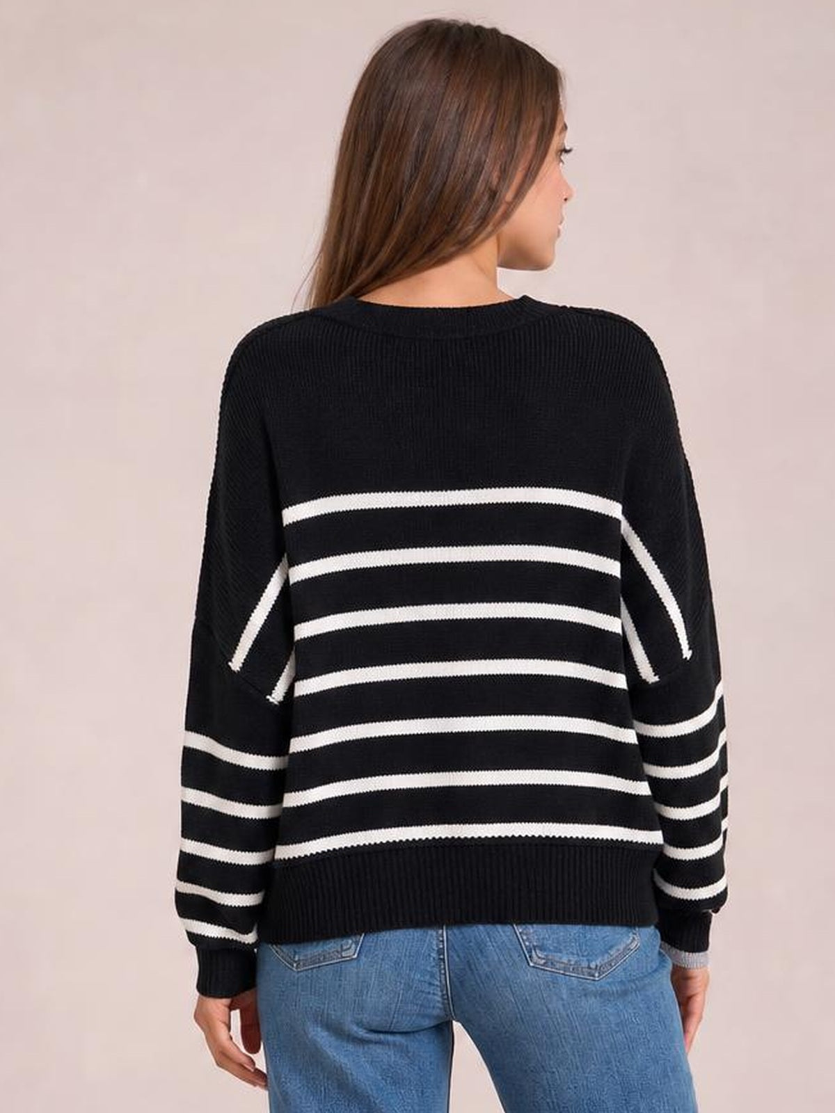 Model turned away wears a black striped round-neck pullover sweater with dropped shoulders, long lantern sleeves, ribbed cuffs and hem, and a regular silhouette.