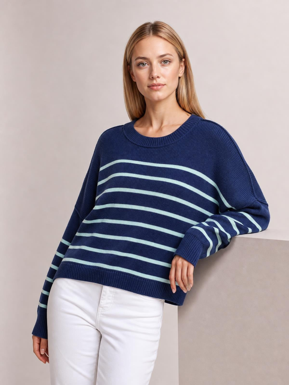A woman wears a navy striped pullover sweater with a round neck, dropped shoulders, long lantern sleeves, ribbed trims, and a relaxed silhouette.