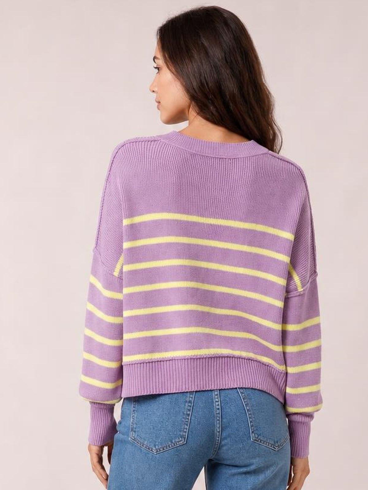 Model shown from behind wearing a lavender striped dropped-shoulder round-neck pullover sweater with yellow bands, long lantern sleeves, and a relaxed regular silhouette.