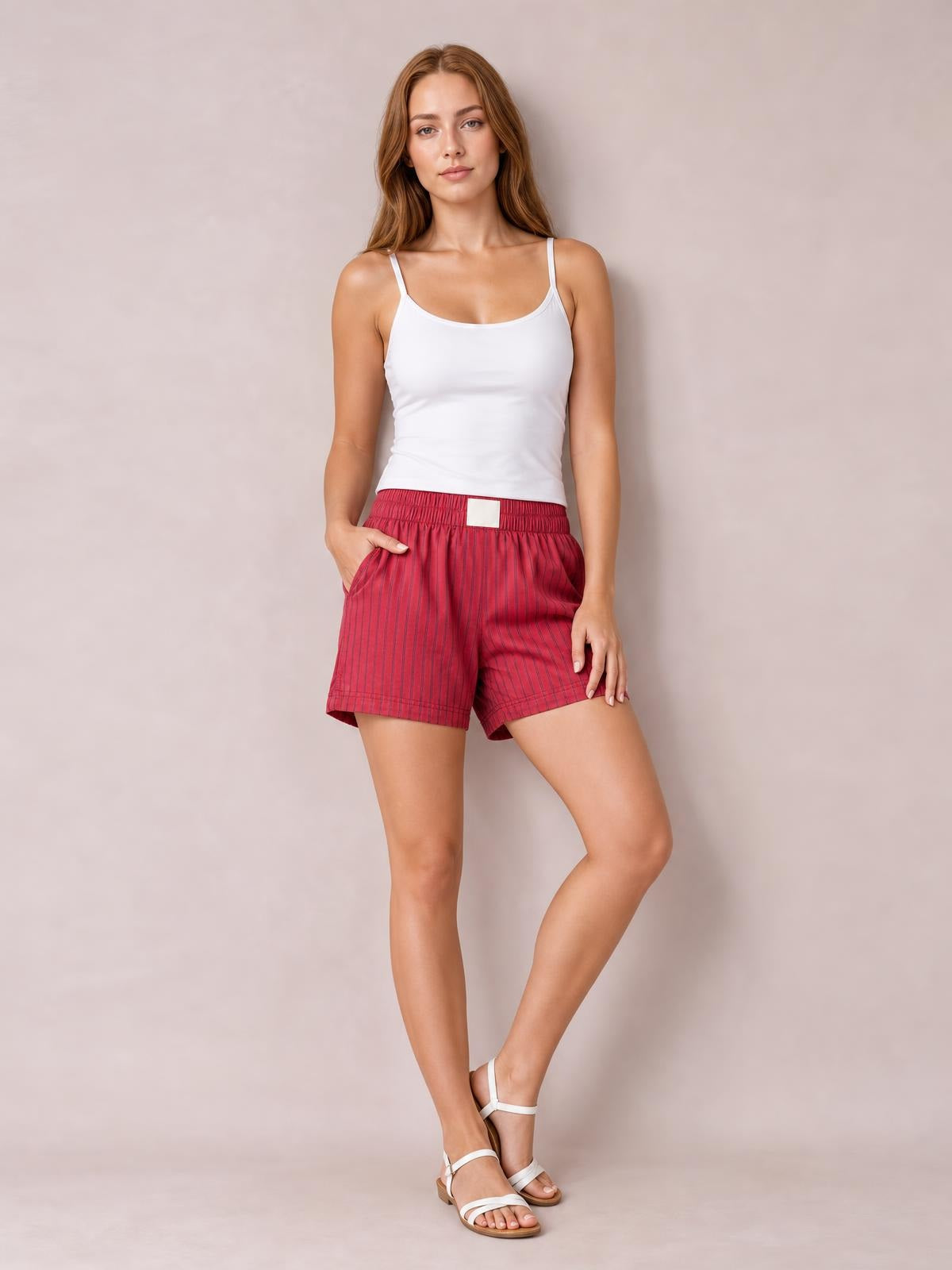 Model poses in red striped elastic-waist shorts with a relaxed straight-leg silhouette and visible side pockets.