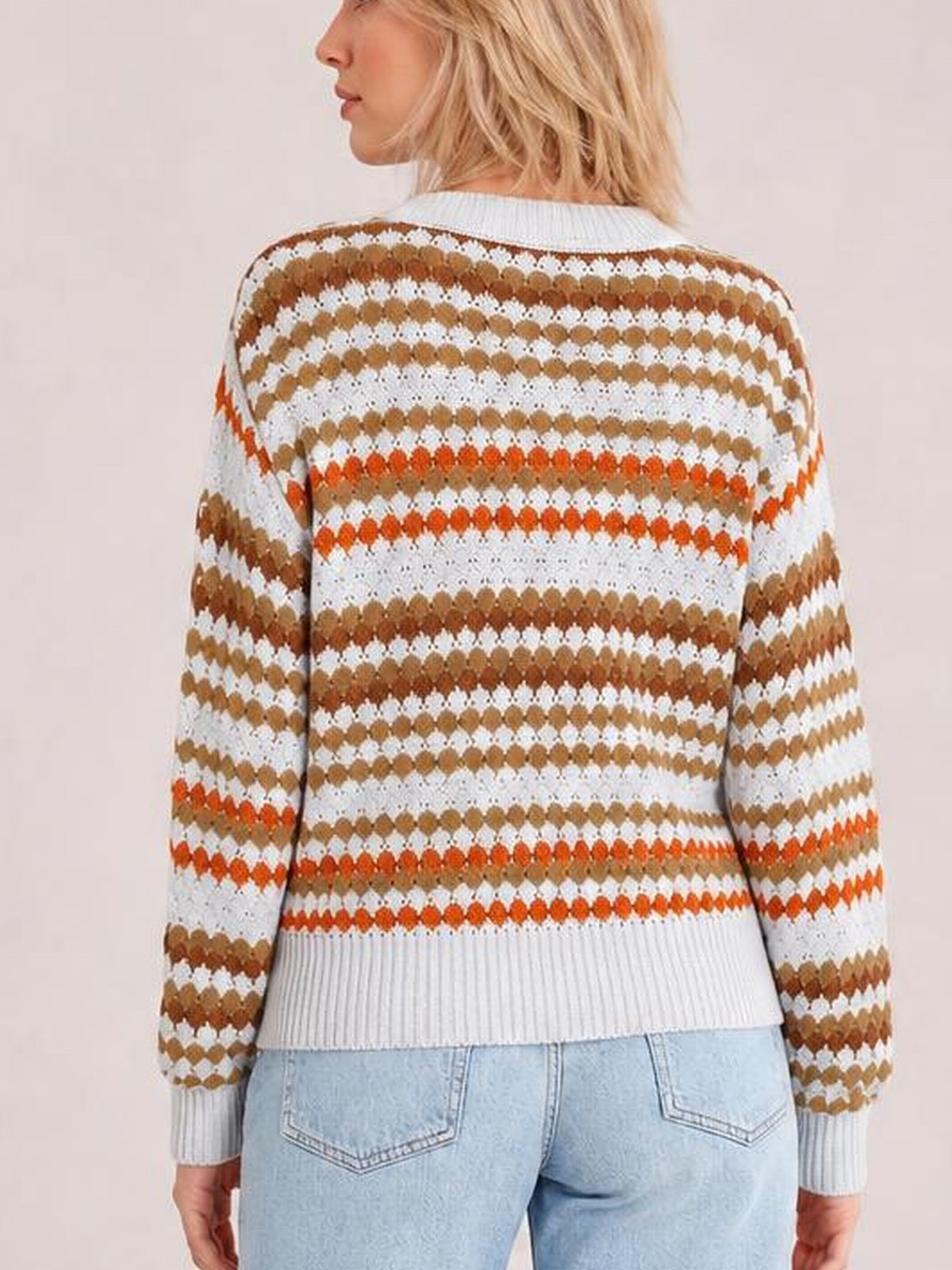 Model shown from the back wears a white striped geometric pattern sweater with brown and orange accents, ribbed crew neck, cuffs, hem, and a relaxed silhouette.