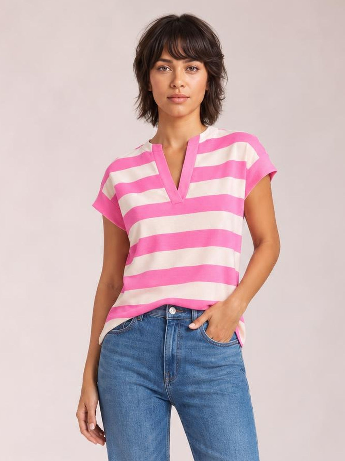 A model stands in a relaxed pose wearing a pink-and-white striped blouse with a notched V-neckline, cap sleeves, and a loose straight silhouette.