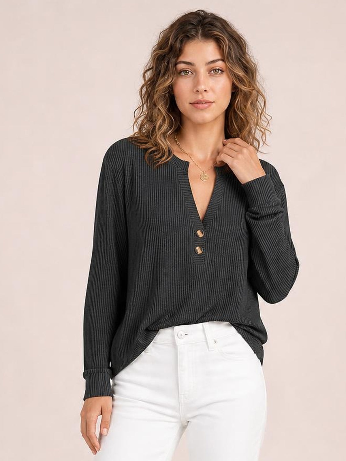 Model wears a dark striped notched long sleeve T-shirt with a relaxed silhouette, ribbed texture, and two button accents, posing with one hand near her collar.