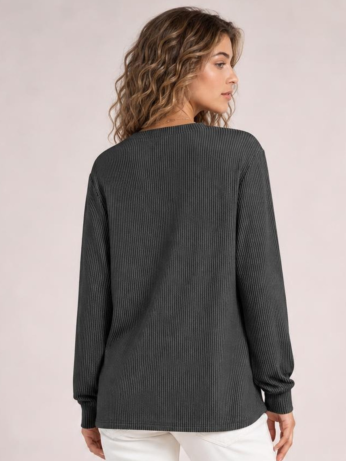 A model looks over her shoulder wearing a charcoal striped long sleeve T-shirt with a relaxed straight silhouette, ribbed texture, and banded cuffs.