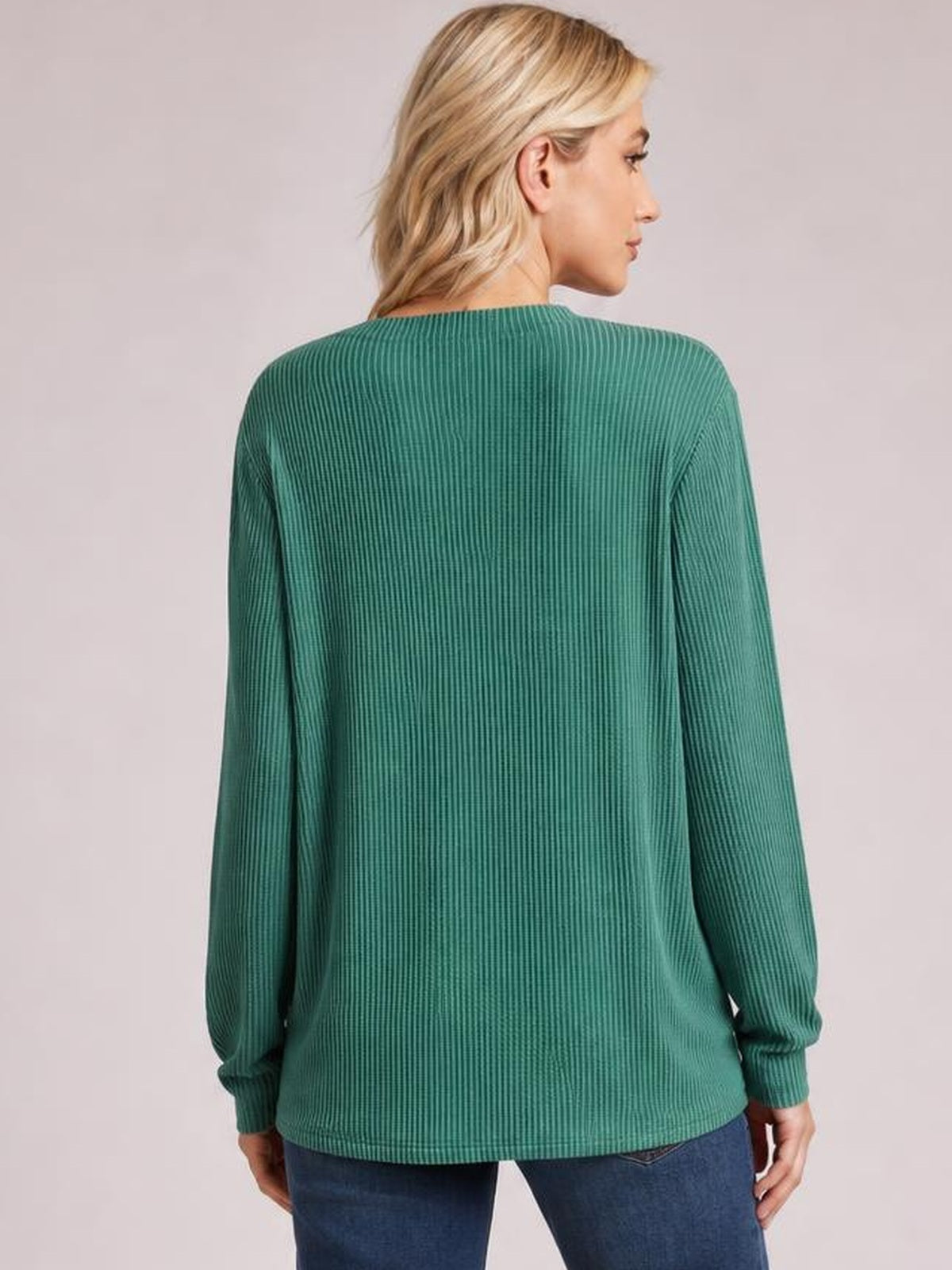 A model wears a green striped long sleeve T-shirt with a relaxed silhouette, ribbed cuffs, and a straight hem, shown from the back in a slight side pose.