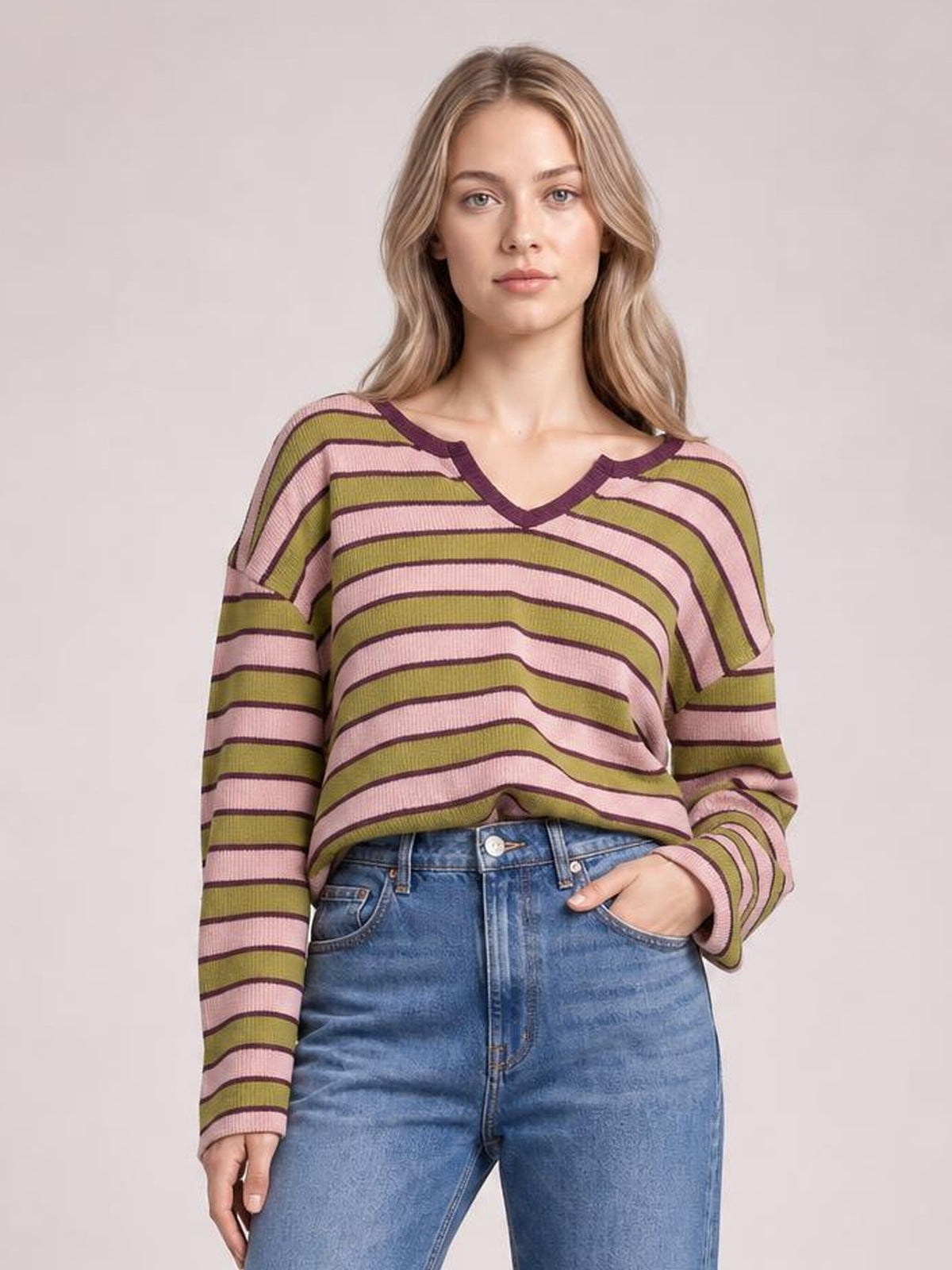 Model wearing an opaque striped notched long-sleeve T-shirt with pink, olive, and burgundy horizontal stripes, a V-shaped neckline, and relaxed silhouette.