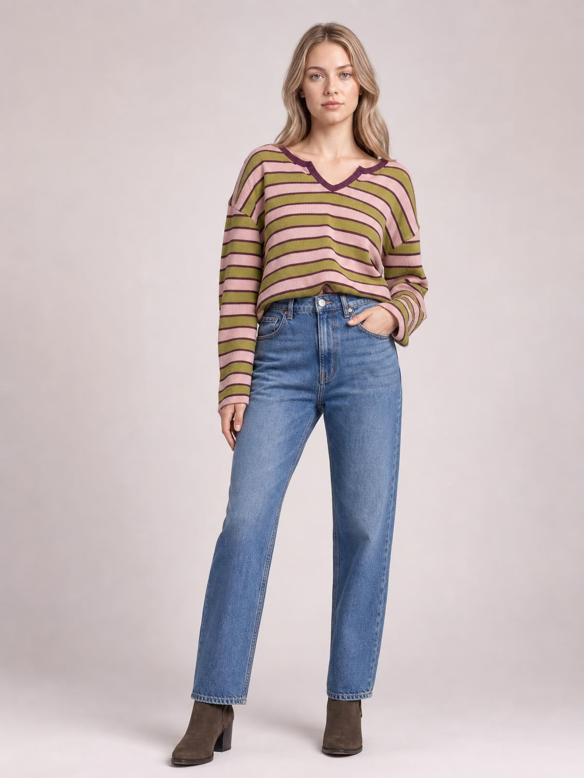 A model stands in a striped long sleeve T-shirt with a notched V-neck, pink, olive, and plum stripes, and a relaxed silhouette.