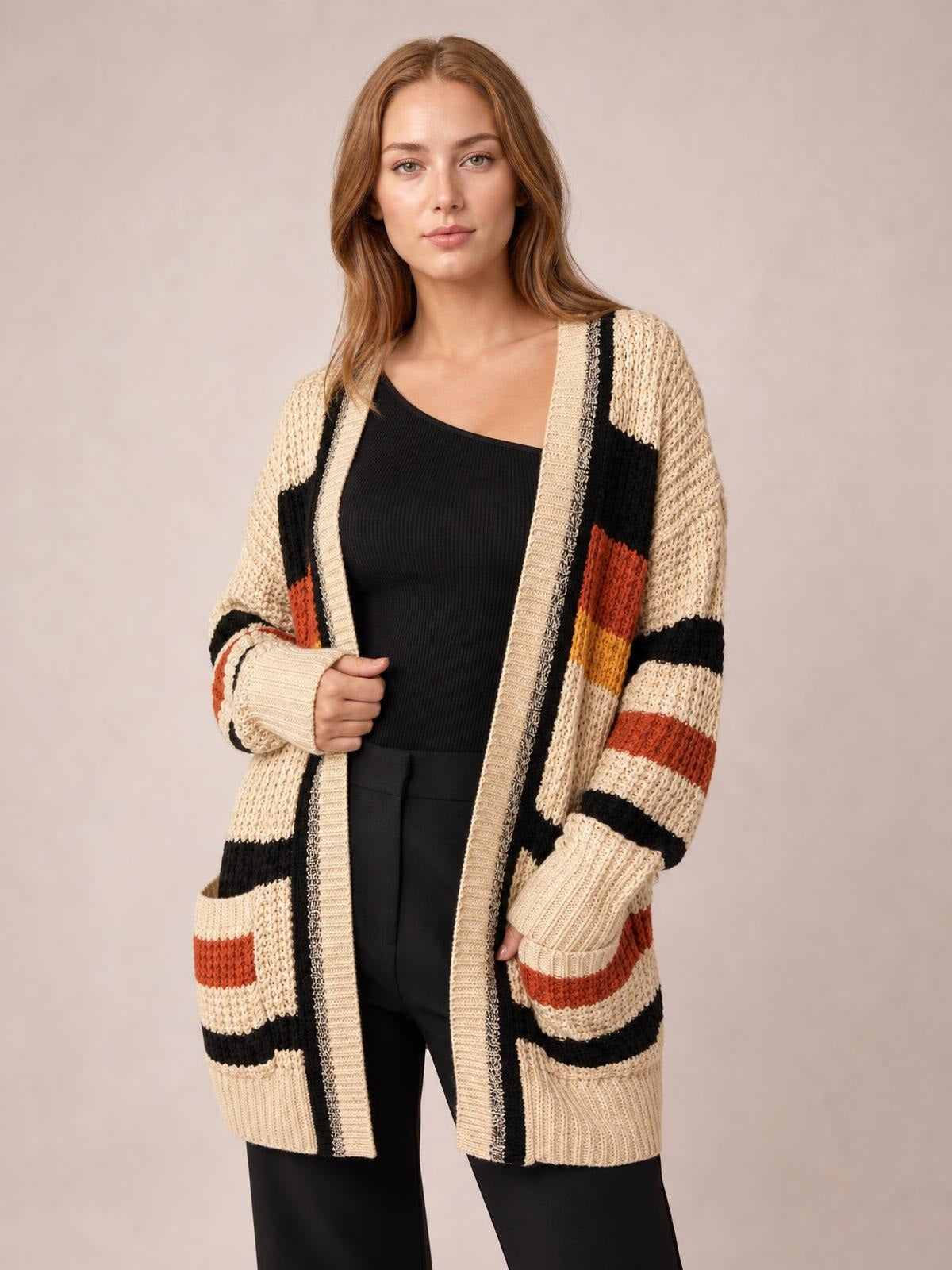 Model wears a cream striped open-front longline cardigan with black and rust accents, ribbed trim, long sleeves, and patch pockets.
