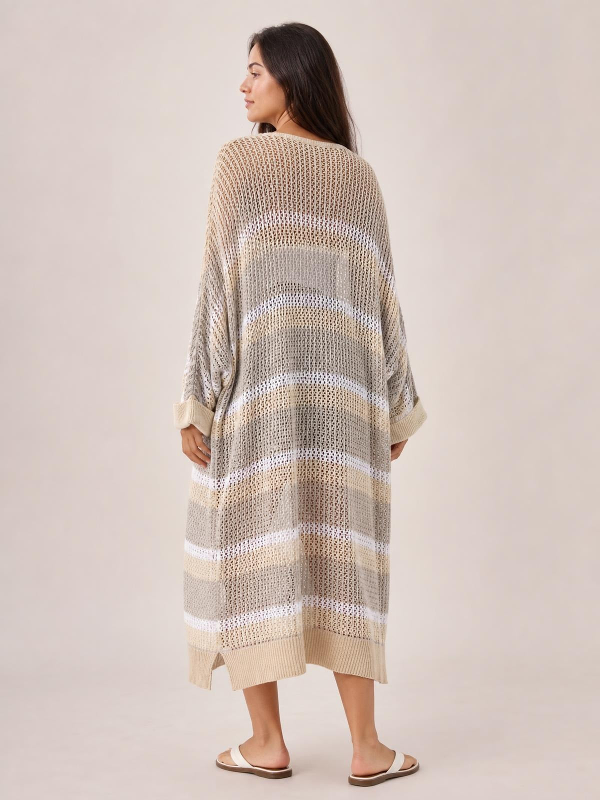Model turned away in a relaxed beige and white striped sheer duster cover up with long sleeves, an oversized silhouette, and side slits.