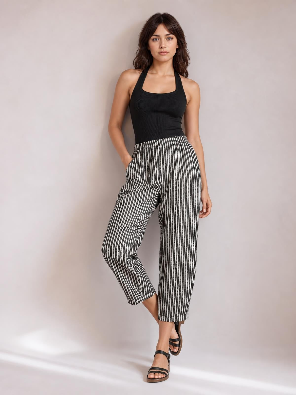 Model poses in black-and-white striped pants with side pockets, a high waist, and relaxed wide-leg cropped silhouette.