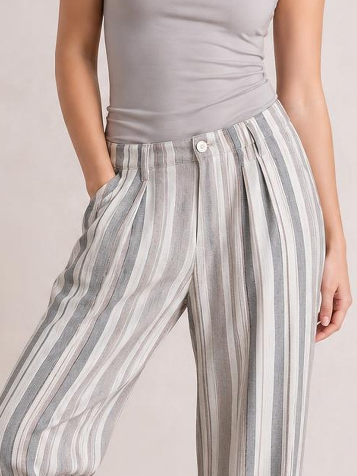 Model wearing gray and white vertically striped pants with an elastic waist, button fly, side pockets, and a relaxed wide-leg silhouette.