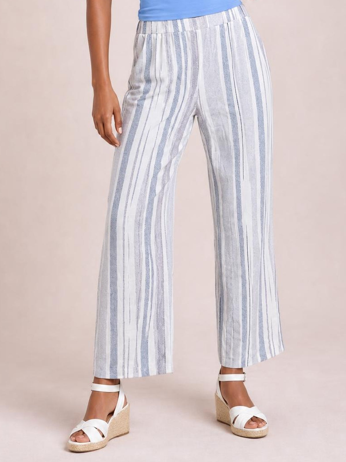 Model wearing opaque white and light blue striped pants with an elastic waistband, straight wide-leg silhouette, and side pockets, standing in wedge sandals.