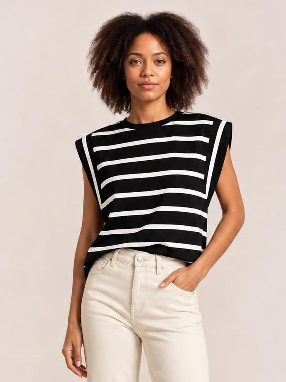 Model wearing a black and white striped round neck cap sleeve T-shirt with a relaxed straight silhouette, standing with one hand in her pocket.