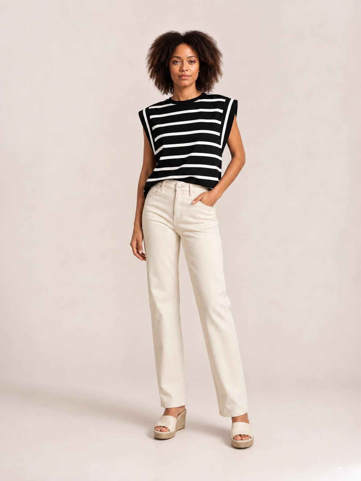 Model wearing a black-and-white striped round neck cap sleeve T-shirt with a relaxed straight silhouette, standing with one hand in her pocket.