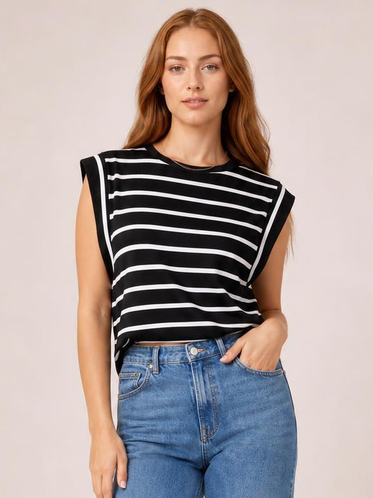 Model wearing a black-and-white striped round neck cap sleeve T-shirt with a relaxed silhouette, standing with one hand in her jeans pocket.