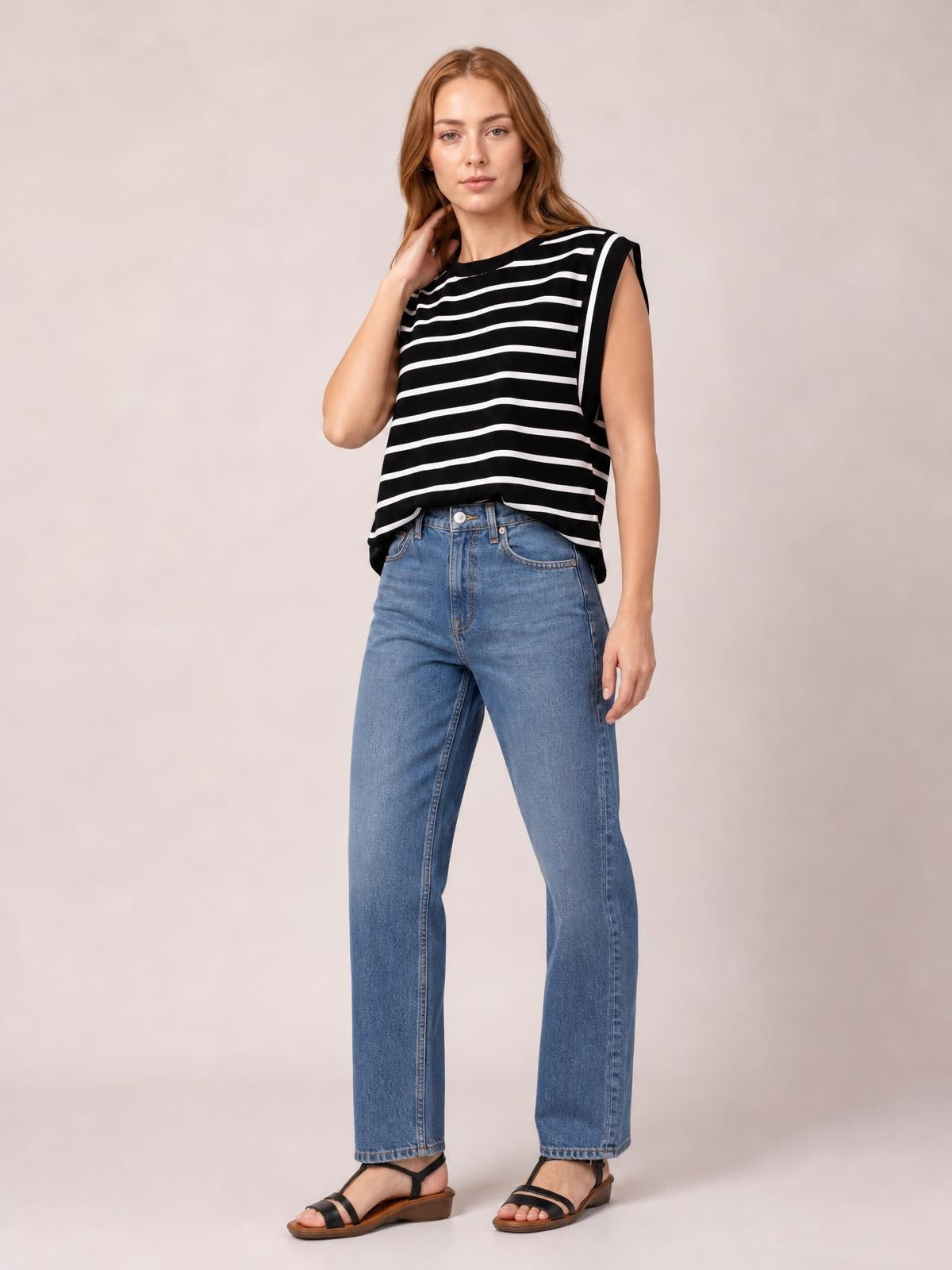 Model wearing a black-and-white striped round neck cap sleeve T-shirt with a relaxed, slightly loose silhouette and curved hem, touching her hair.