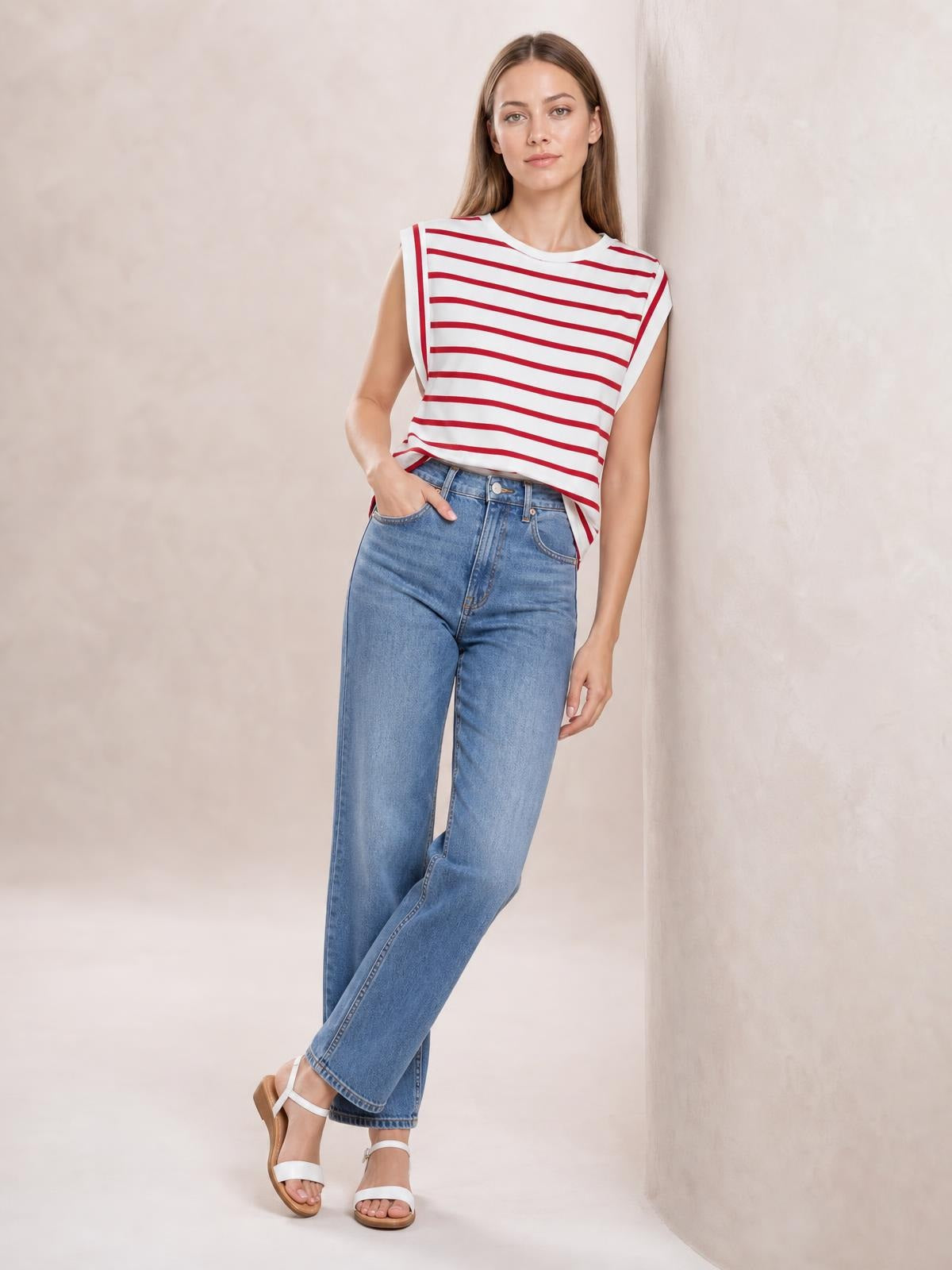 Model wears a white striped round neck cap sleeve T-shirt with red horizontal stripes and a relaxed silhouette, posing with one hand in her jeans pocket.