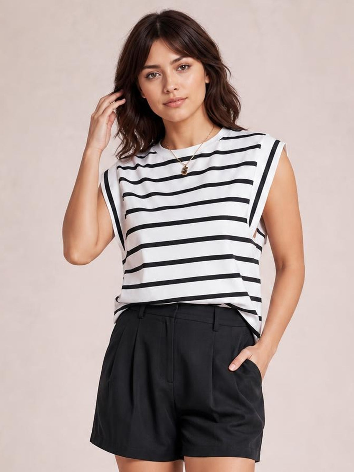 Model wearing a white and black striped round neck cap sleeve T-shirt with a relaxed silhouette, standing with one hand in her pocket.