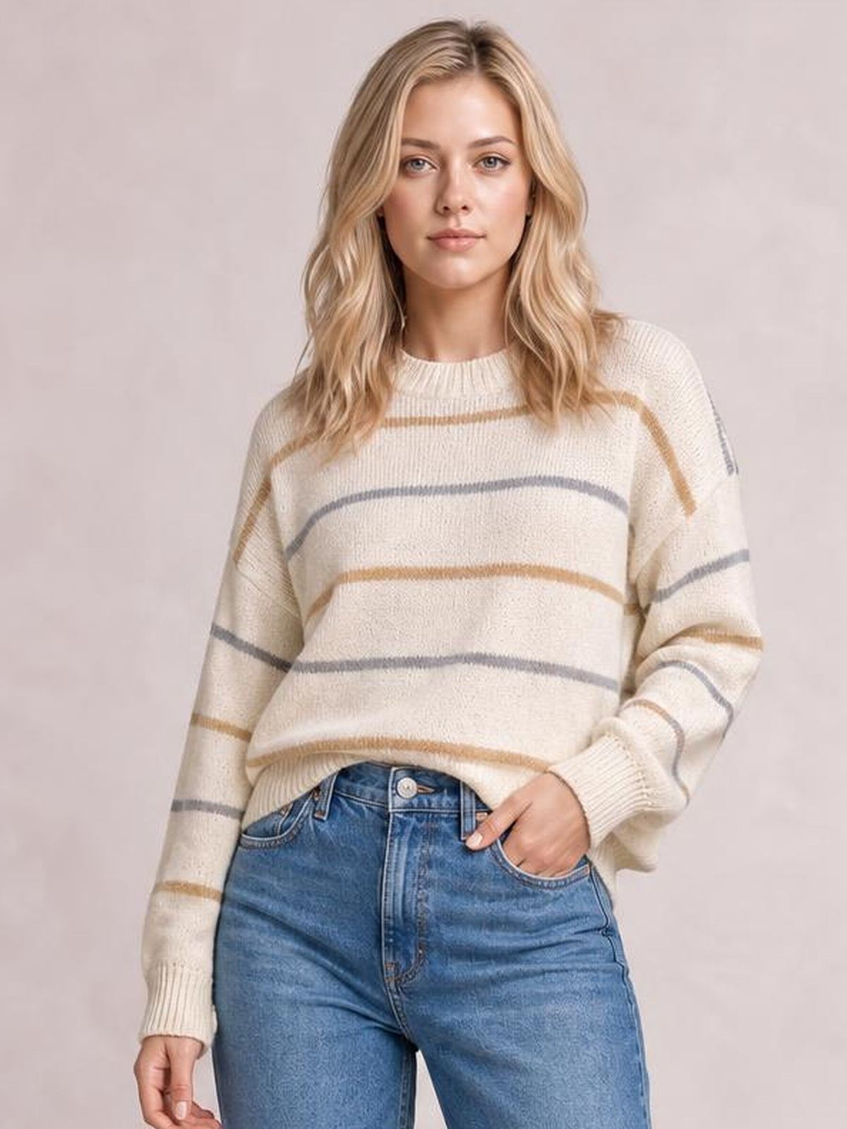 Model wearing a cream striped round-neck drop-shoulder sweater with a relaxed silhouette, long sleeves, and ribbed cuffs and hem.