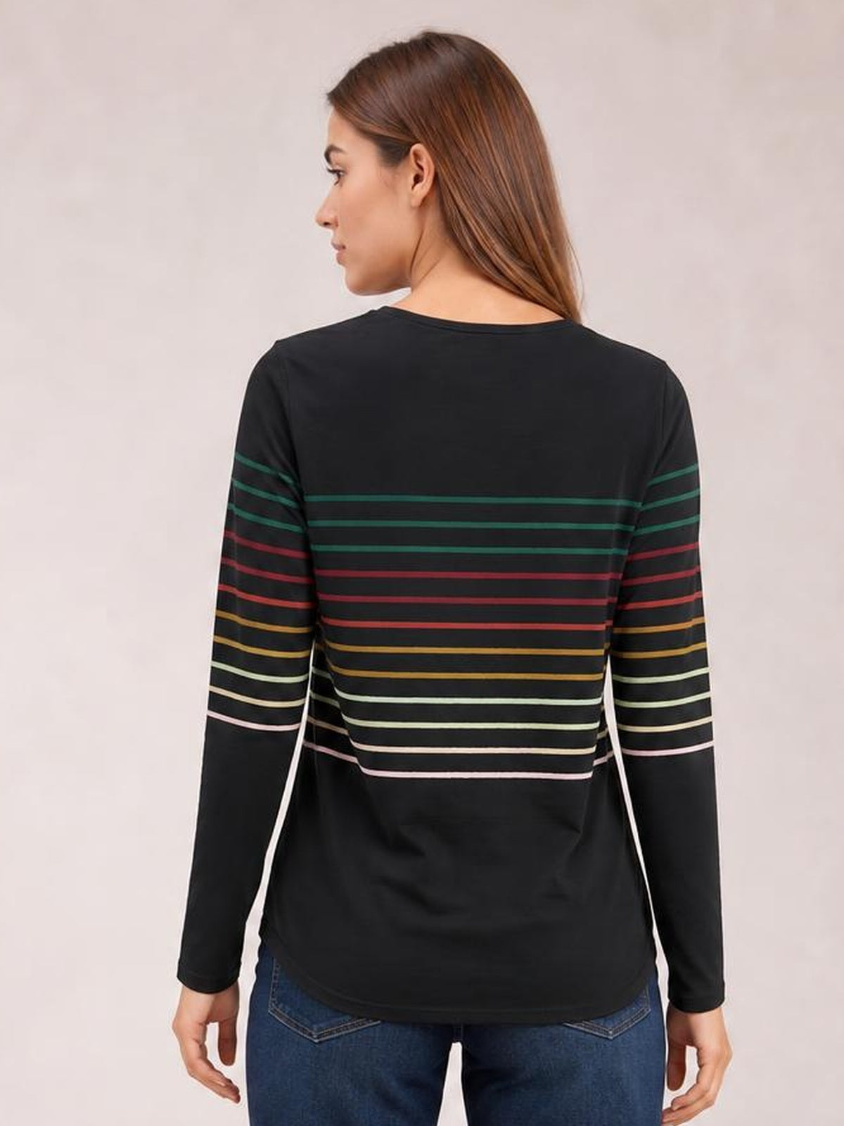Model shown from the back wearing a black striped round neck long sleeve T-shirt with multicolor horizontal bands and a relaxed, straight silhouette.