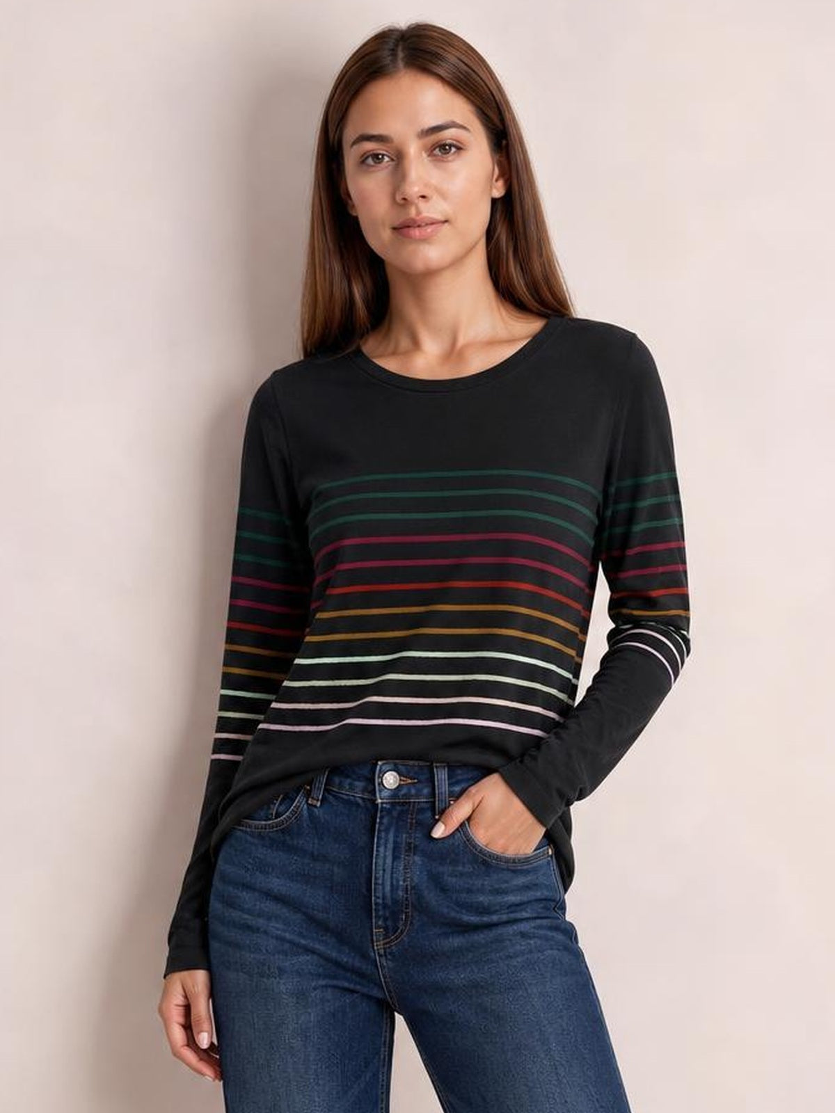 Model poses in a black striped round neck long sleeve T-shirt with multicolored horizontal bands, relaxed silhouette, and slightly stretchy construction.