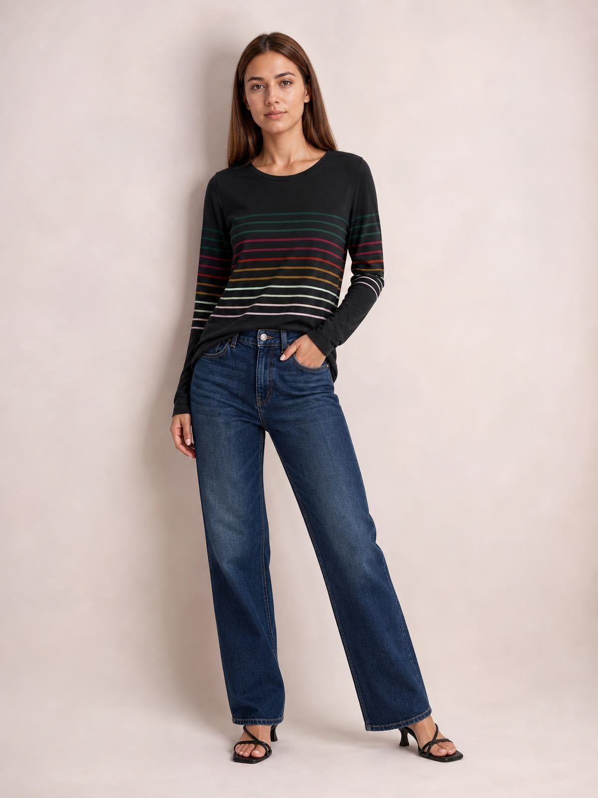 Model poses in a black round-neck long-sleeve T-shirt with multicolor horizontal stripes and a relaxed, slightly fitted silhouette.