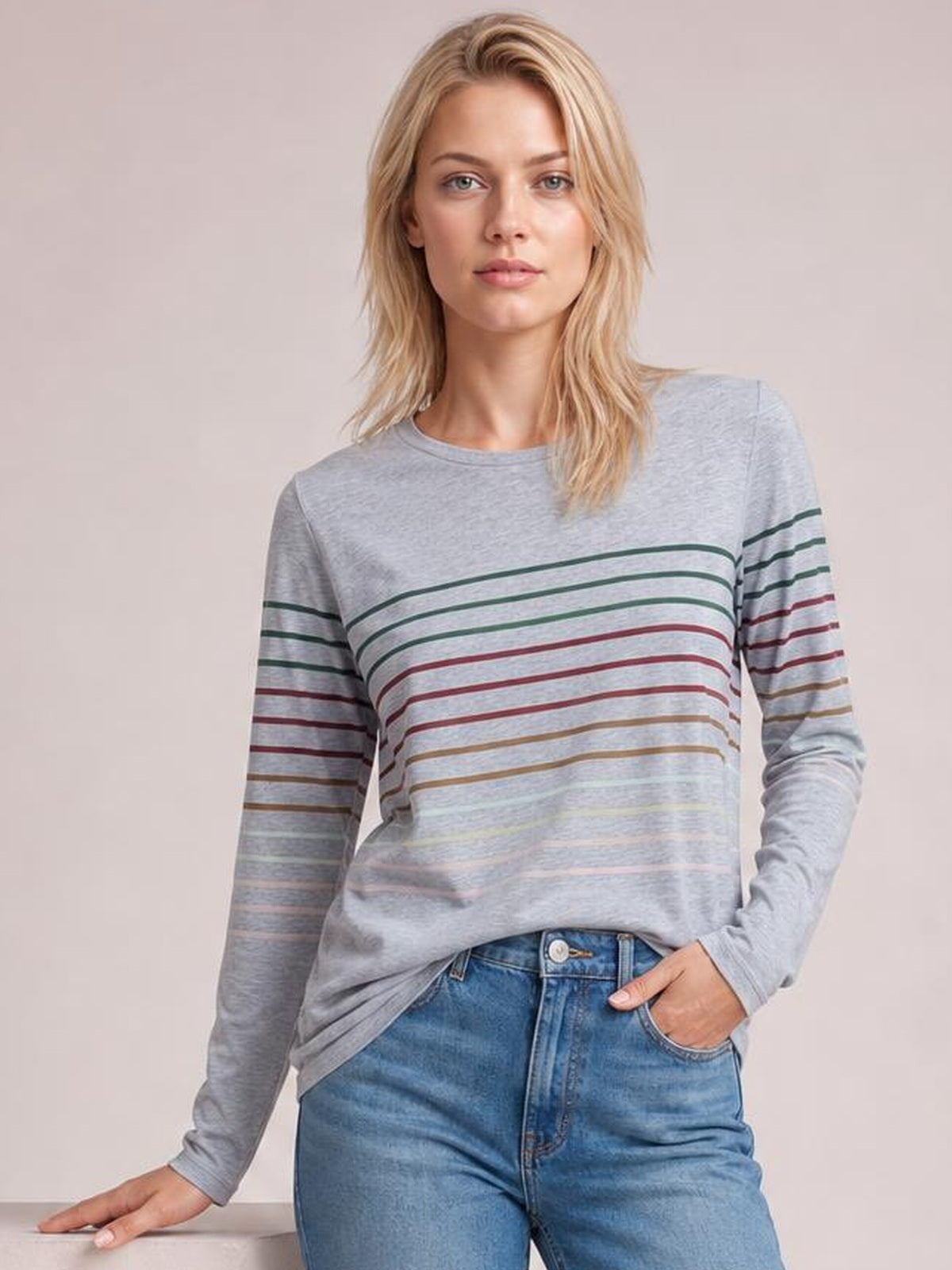 Model wearing a light gray striped round neck long sleeve T-shirt with multicolor horizontal stripes and a relaxed, slightly fitted silhouette.