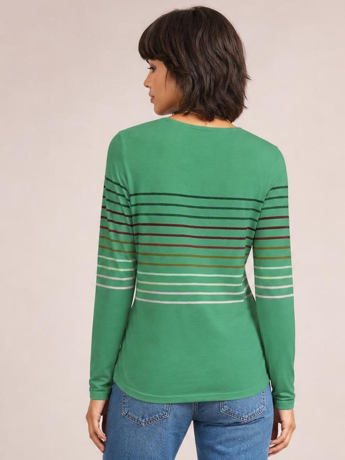 Model shown from behind wearing a green striped round neck long sleeve T-shirt with horizontal multicolor bands and a relaxed silhouette.