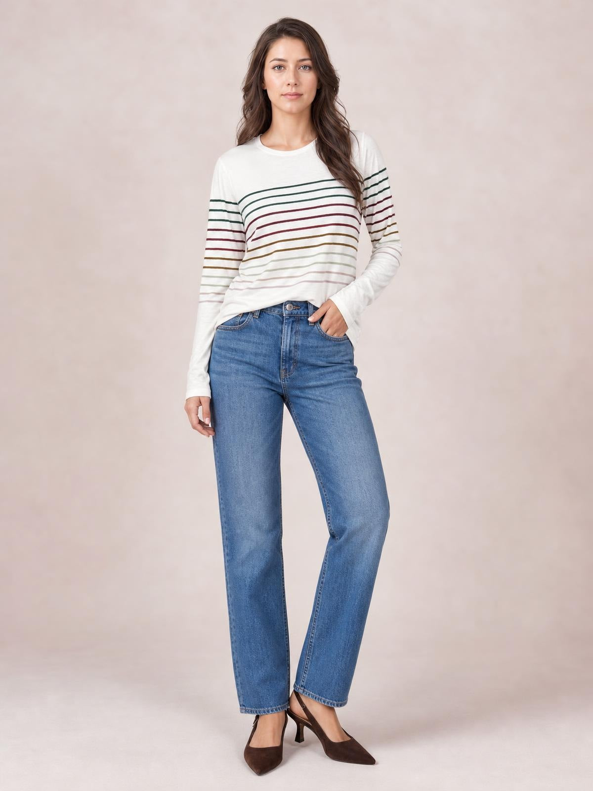 Model wears a soft white striped round neck long sleeve T-shirt with a relaxed silhouette, standing with one hand in her jeans pocket.